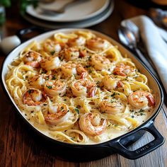 pasta with shrimp and parmesan cheese in a skillet on a wooden table