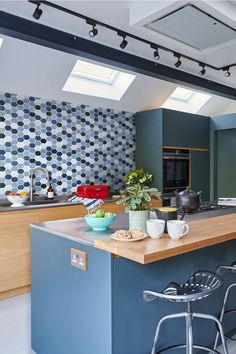 a kitchen with an island and skylights in the ceiling, along with two stools