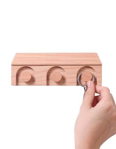 a hand holding a wooden block with three circles on it and two rings in the middle