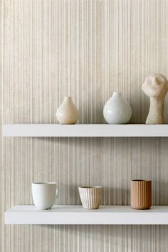 three white shelves with vases and cups on them