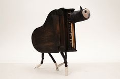 a toy horse that is standing next to an old piano with it's legs sticking out