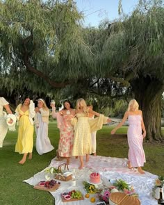 a group of women standing around a table with food and drinks on top of it