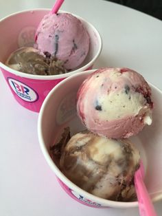 two ice creams in pink cups on a table