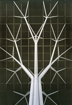 a white tree sculpture sitting in front of a wall with metal squares on it's sides