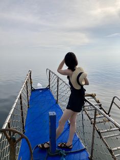 a woman standing on the edge of a boat looking at the water