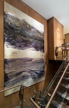 an abstract painting hangs on the wall next to a stair case in a modern home