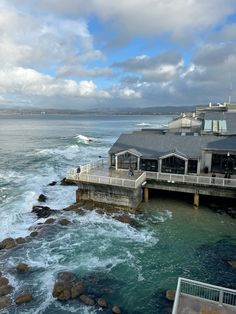 an ocean view with waves crashing in to the shore and a restaurant next to it