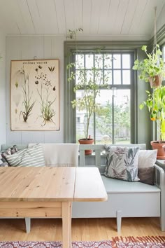 a living room filled with furniture next to a window covered in plants and potted plants