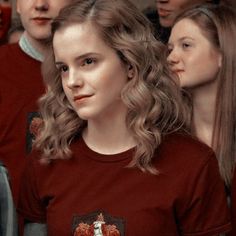 a group of young people standing next to each other in front of a mirror with one girl wearing a red shirt