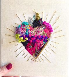 a heart - shaped brooch is adorned with colorful flowers and hair pins on a white background