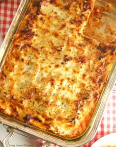 a casserole dish with cheese and meat on a checkered tablecloth, ready to be eaten