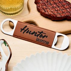 a bottle opener sitting on top of a wooden table next to a plate and knife