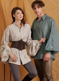 a man and woman standing next to each other in front of a yellow wall with curtains