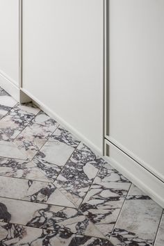 a white kitchen with marble flooring and cabinets in the corner by the countertop