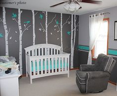 a baby's room decorated in gray and turquoise with birch trees painted on the wall