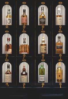 an assortment of different types of liquor bottles in front of a black wall with gold trim