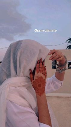 a woman with henna on her head and hands covering her face is looking into the distance