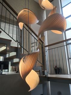 several lights hanging from the ceiling in a room with stairs and railings, along with two people sitting at a table