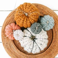 four crocheted pumpkins sitting on top of a wicker plate with string