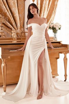 a woman is posing in front of a piano wearing a white dress with thigh high slit