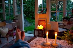 a person sitting in front of a fireplace with two lit candles on top of it