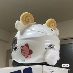 a white helmet with ears and nose stickers on it sitting next to a box