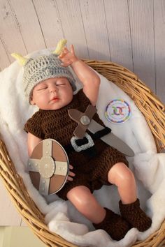 a baby doll is laying in a basket with a hat on it's head