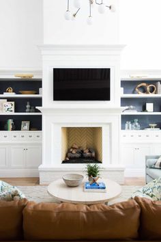 a living room with couches and a tv above the fireplace in it's center