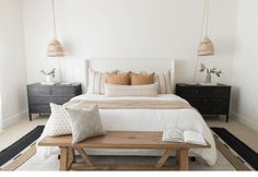 a bedroom with white walls and wooden furniture, including a large bed in the center