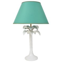 a white lamp with a green shade on it's base and palm tree design