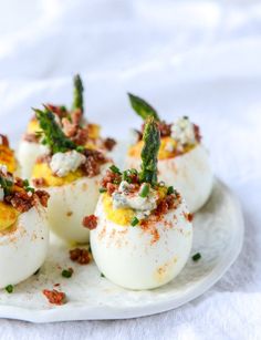 four deviled eggs on a white plate topped with green garnish