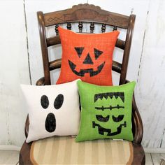 three halloween pillows sitting on top of a wooden chair