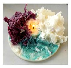 a white plate topped with lots of different colored food on top of a table next to a candle