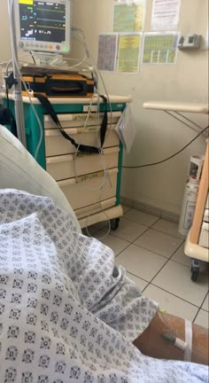 a hospital room with medical equipment and patient's hand on the bed in it