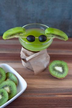 a bowl filled with kiwis and sliced bananas on top of a wooden table