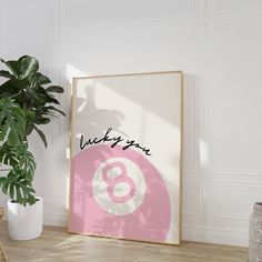 a pink and white poster with the words lucky you on it next to a potted plant