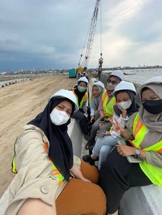 four women in hijabs and safety vests sitting on the back of a boat