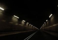 a dark tunnel with lights at the end and no one in it on the other side