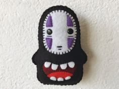 a black and white stuffed animal with purple eyes on it's face is hanging from the wall