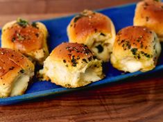 small rolls covered in cheese and herbs on a blue platter with a wooden table