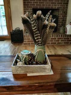 a vase filled with feathers sitting on top of a wooden table next to a fire place