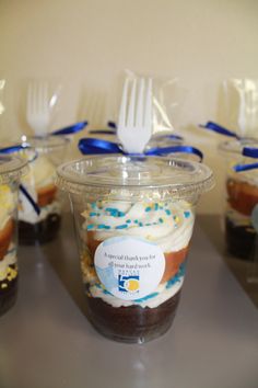 cupcakes with frosting and sprinkles in plastic cups on a table