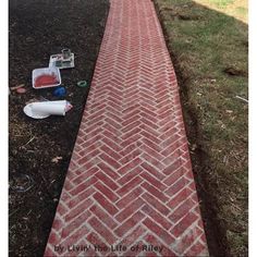 a red brick walkway with some trash on the ground next to it and an empty bottle