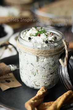 a glass jar filled with food sitting on top of a plate next to crackers