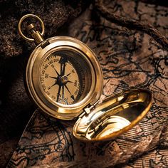 a gold pocket watch sitting on top of a map