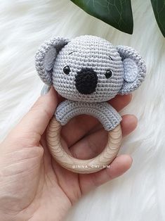 a crocheted koala bear holding a wooden ring in it's hand