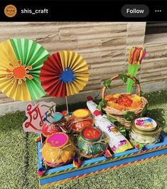 an assortment of colorful items on display in the grass with paper umbrellas above them