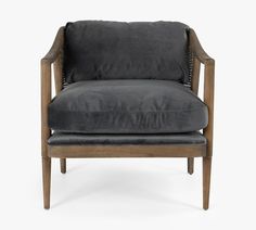 a gray velvet chair with wooden legs and arm rests on an isolated white background,