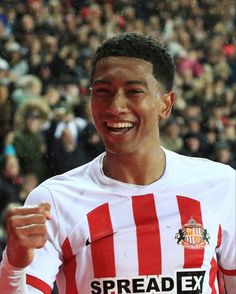 a young man is smiling and holding his fist up in front of an audience at a sporting event