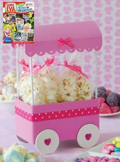 a pink wagon filled with popcorn and marshmallows on top of a table